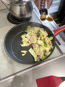 胸肉と野菜を炒めて豆板醤をかける様子